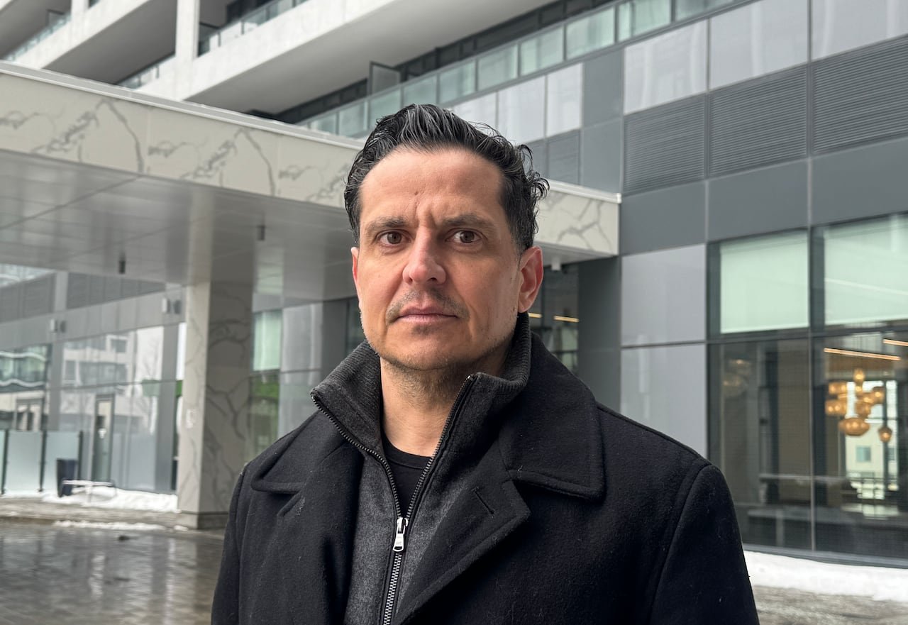A man stands in front of a condo building