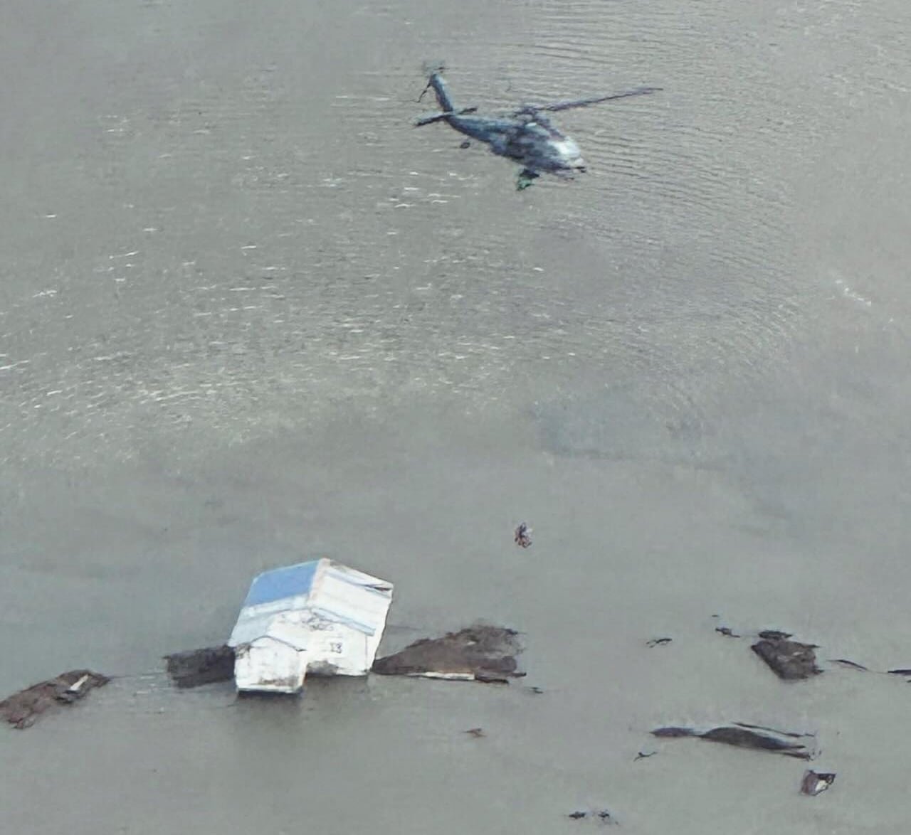 Aerial view of a helicopter above a flooded home.
