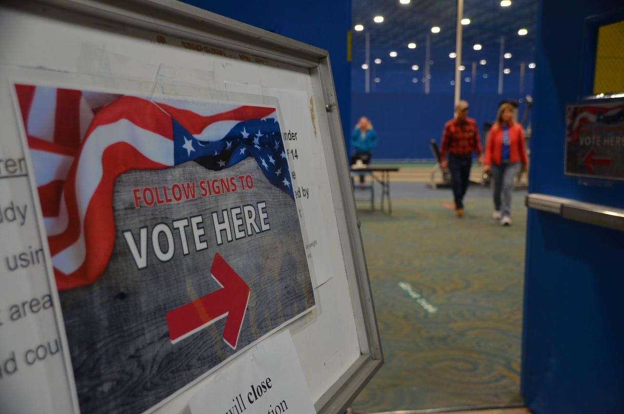 A sign reads 'Follow signs to vote here' with some people in the background