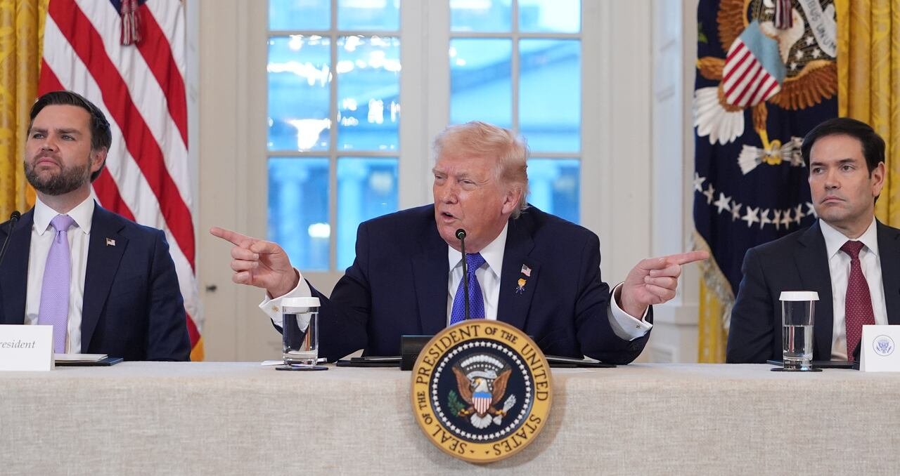 The President gestures with his fingers while talking into a microphone.