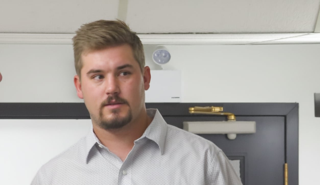 A man in a white shirt looks away from the camera