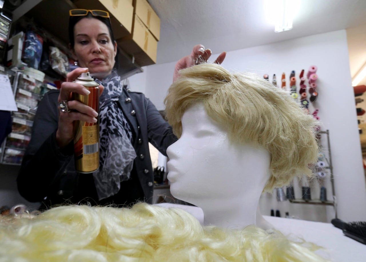 A person applies a spray to a wig.