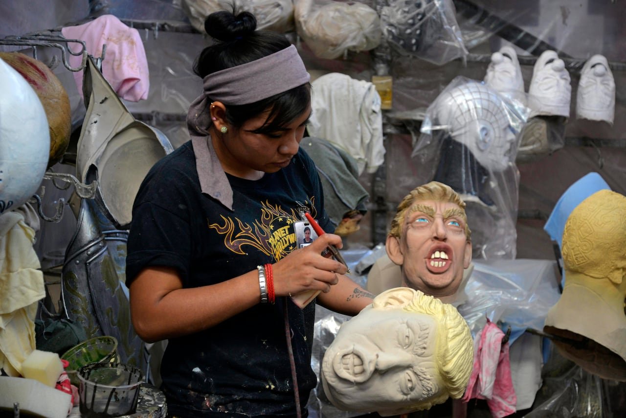 A worker applies spray paint to a mask.