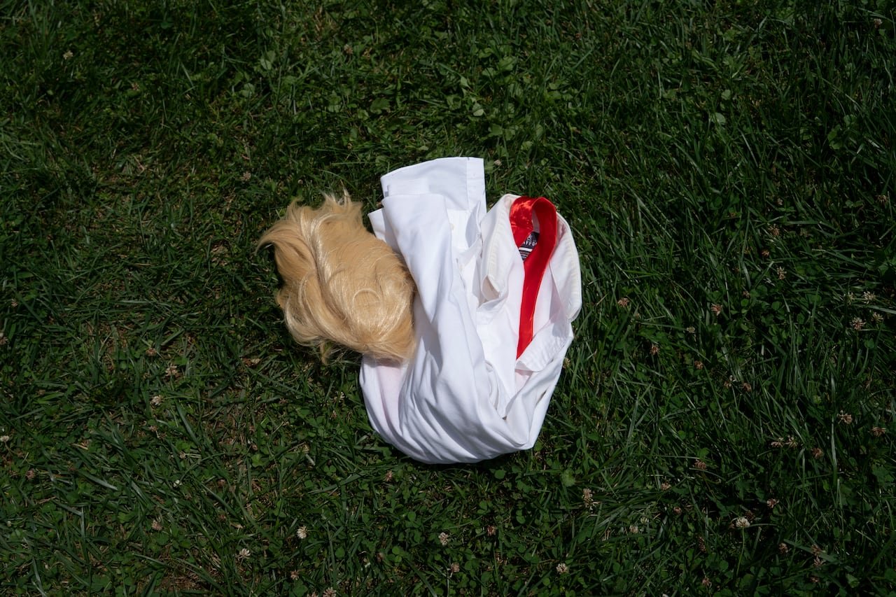 A wig, tie and shirt are seen on grass.