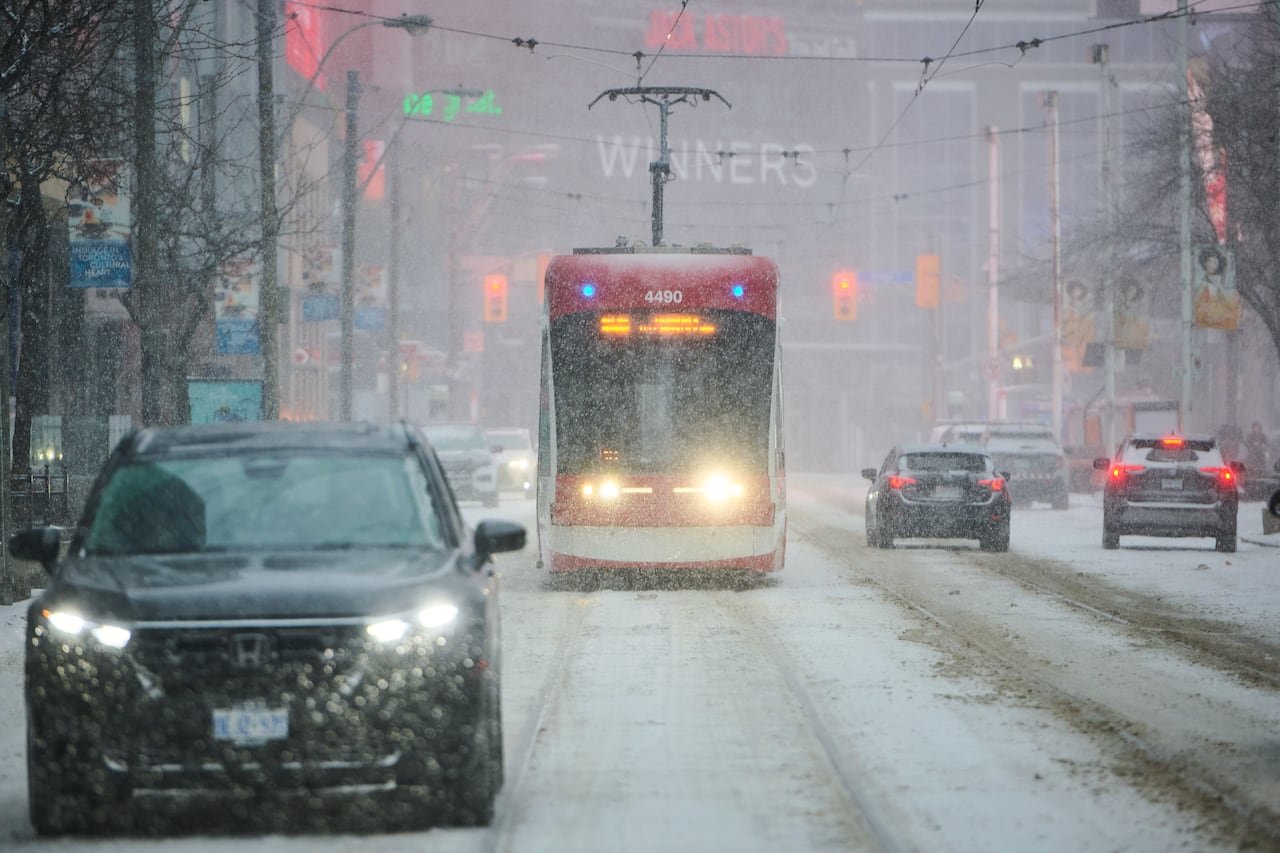 default-195 A streetcar makes its way down a snow-covered road.