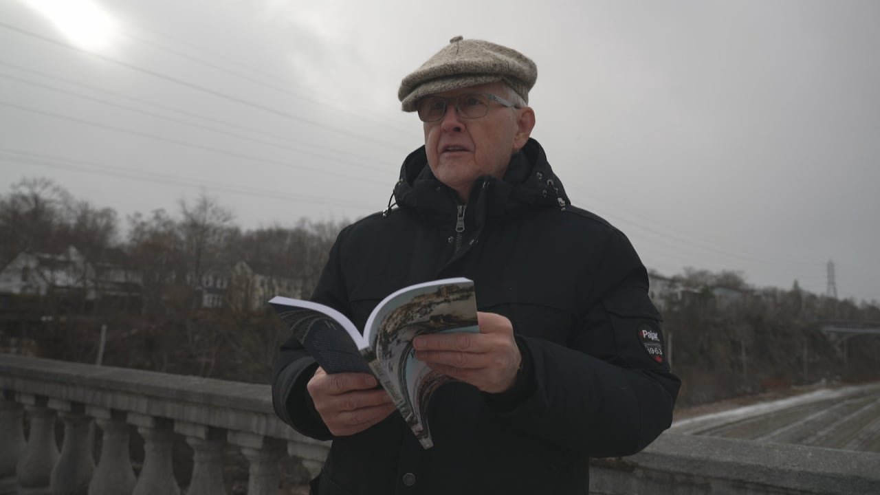 default-332 A man in a tam o' shanter, holds a book while standing on a bridge over the rail cut